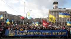 Οι διαδηλωτές κρατούν πανό και σημαίες καθώς συμμετέχουν σε συγκέντρωση ενάντια σε ενδεχόμενη κλιμάκωση της έντασης μεταξύ Ρωσίας και Ουκρανίας.