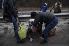 Qualcuno viene aiutato a strisciare sotto una barriera di sicurezza al centro della strada mentre fuggono