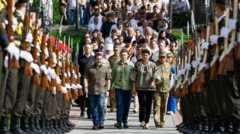 People walk alongside a military guard at a ceremony at the graves of fallen soldiers in Lychakiv cemetery