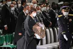 The widow of former Japanese prime minister Shinzo Abe, Akie Abe (C), carries his ashes as she arrives for the start of his state funeral at the Nippon Budokan in Tokyo on September 27, 2022.