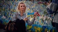 девушка на фоне украинских флагов показывает имя родственника