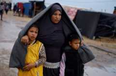 Displaced Palestinian woman takes shelter in Gaza with her children during heavy rainfall