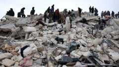 Residents and rescuers search for victims and survivors amidst the rubble of collapsed buildings following an earthquake in the village of Besnaya in Syria's rebel-held north-western Idlib province on the border with Turkey