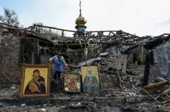 Женщина собирает православные иконы на месте разрушения храма в поселке Камышеваха Запорожской области Украины, 16 апреля 2023 года.