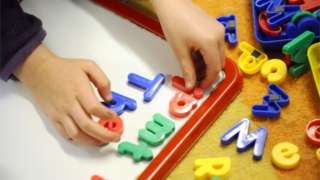 Child playing with brightly-coloured magnetic letters