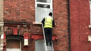 A council worker boarding up the house