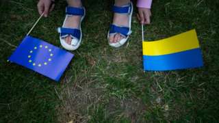 A Ukrainian girl holds both EU flag and Ukraine flag during the March supporting Ukraine for EU candidate membership in Duesseldorf on June 19, 2022 (