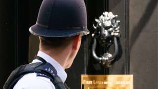 Police officer looks at the door of 10 Downing Street