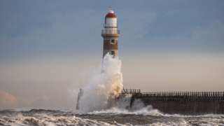 Waves break around lighthouse at Roker