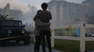 Biviana Faut (L) and Christian Faut comfort each other as they look on at the partially collapsed 12-story Champlain Towers South condo building on June 25, 2021 in Surfside, Florida.