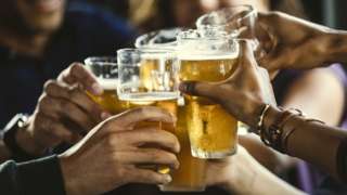 Stock image of drinkers clinking pint glasses together