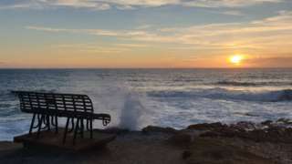 A bench by the sea at sunset at Treyarnon Bay in Cornwall