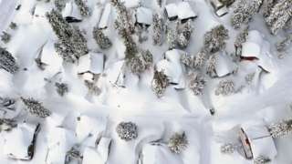 In an aerial view, snow covers roofs next to snowbanks piled up from new and past storms in the Sierra Nevada mountains, in the wake of an atmospheric river event, on March 12, 2023 in Mammoth Lakes, California