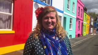 Tash Frootko founder of the Rainbow House project stood in front of colourful houses