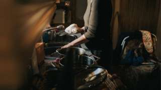 Woman in kitchen of messy house