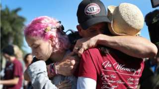 Anthony Gonzalez hugs his daughter, Victoria Gonzalez and her teacher Ronit Reoven (L-R), as they visit a memorial setup near Marjory Stoneman Douglas High School .