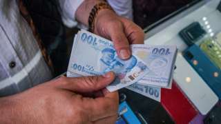A man counts Turkish lira notes