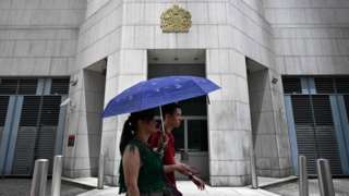 Pedestrians walk past the British Consulate-General building in Hong Kong