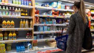 A woman holding a shopping basket while shopping in a supermarket