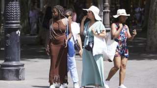 Four women wear hats to protect them from the heat in Seville.