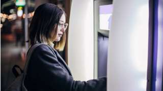 Woman withdrawing money from ATM machine