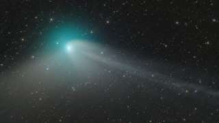 Green comet with long tail against starry black background