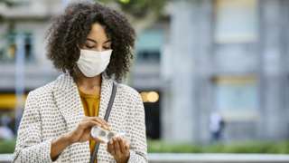 Woman wearing mask with hand sanitizer