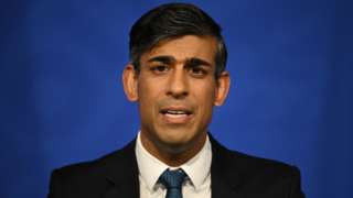 PM Rishi Sunak speaks in front of a blue background