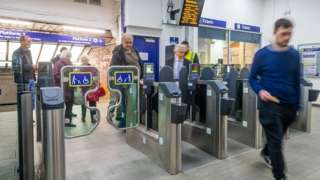People using ticket barriers at a railway station