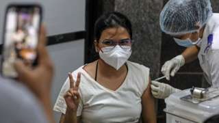 A woman gestures as she gets her first dose of a Covid-19 vaccine shot, manufactured by Serum Institute of India, inside a Vaccination Centre at Shatabdi Hospital in Mumbai, India, 12 March 2021