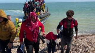 Men holding hands as they climb off a boat onto shore