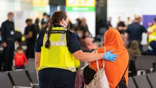 UK Border Force staff assisting a female evacuee as refugees arrive from Afghanistan at Heathrow Airport