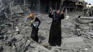 A Palestinian woman pauses amid destroyed buildings in the northern district of Beit Hanun in the Gaza Strip during an humanitarian truce on 26 July 2014
