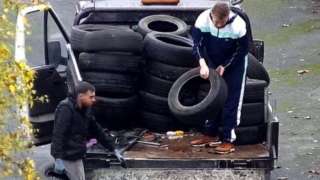 CCTV camera still of two men on a truck loaded with tyres, with other tyres on the ground