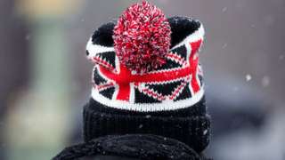 A person wears a Union Flag bobble hat during wintery weather in London