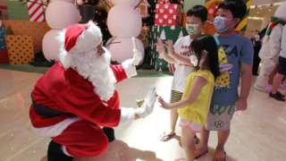 A man dressed as Santa Claus greets children at a shopping mall in Jakarta on December 25, 2020.