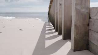 Beach posts reflected in sand at Dawlish Warren, Devon