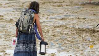 Woman walks through muddy ground at Burning Man