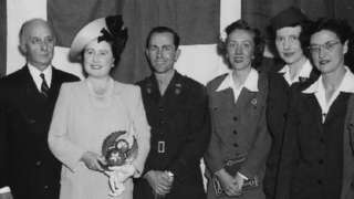 Queen Elizabeth The Queen Mother posing with a number of people and Emily Harper Rea, second from left