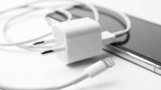 iPhone charging cable and USB power adapter lying on top of an iPhone