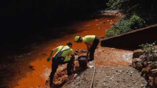 Ecologists from the Ecolive organization take samples of sludge caused by the polluted water flow from the nearby siderite mine shafts near Nizna Slana, Slovakia on August 11 2022
