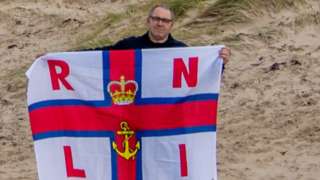 Chris Mason holds RNLI flag