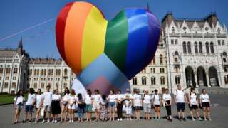 Activists gather in front of a huge heart-shaped rainbow balloon