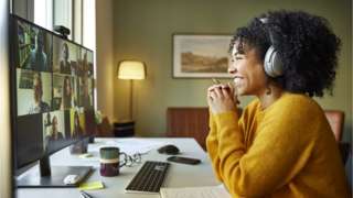 Businesswoman with headphones smiling during video conference.