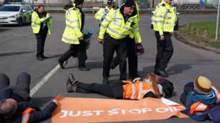 Police officers look at activists from Just Stop Oil taking part in a blockade at the Kingsbury Oil Terminal, Warwickshire