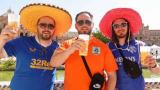 Rangers fans wearing sombreros and drinking beer pose for a photo
