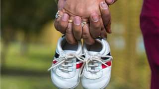 An Indian couple hold baby shoes