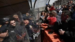 Police face migrants at the US-Mexico border on Sunday