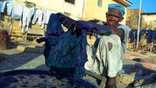 Local dyer Baba Muhammed dips cloth into dye bit in Kano, Nigeria