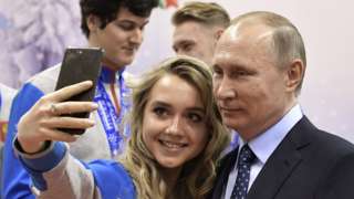 Vladimir Putin posing for a selfie with a Russian athlete
